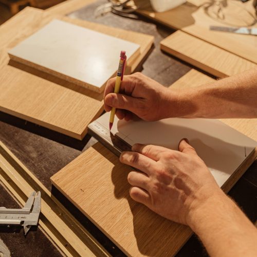 pexels-photo-5466151-5466151 A skilled woodworker measuring wood pieces in an indoor workshop.
